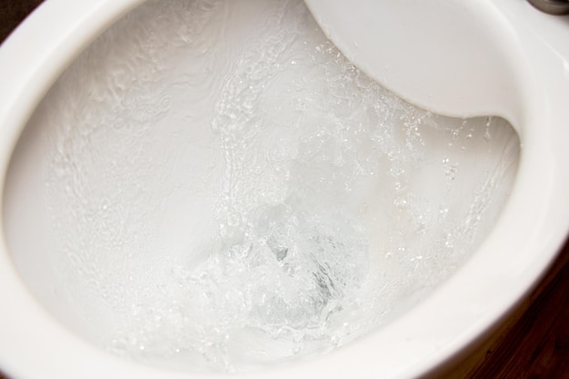 Toilet while flushing urine with water A stream of water in the toilet bowl