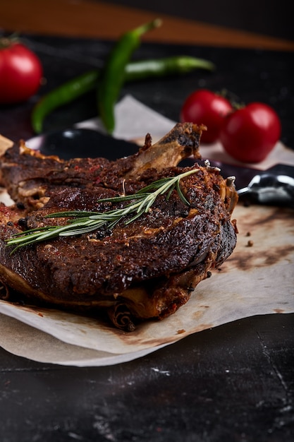 Tomahawk steak with vegetables and a knife on the table. Grilled meat with grilled vegetables and fresh vegetables on the table.