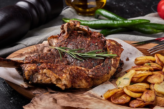 Tomahawk steak with vegetables and a knife on the table. Grilled meat with grilled vegetables and fresh vegetables on the table.