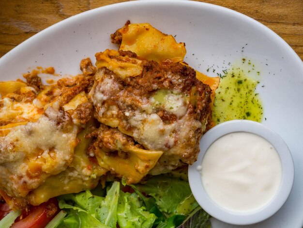 Tomato and beef lasagne with cheese layered between sheets of traditional Italian pasta served on a white plate