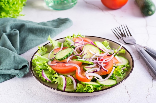 Tomato cucumber onion lettuce salad on a plate on the table Vegetarian food