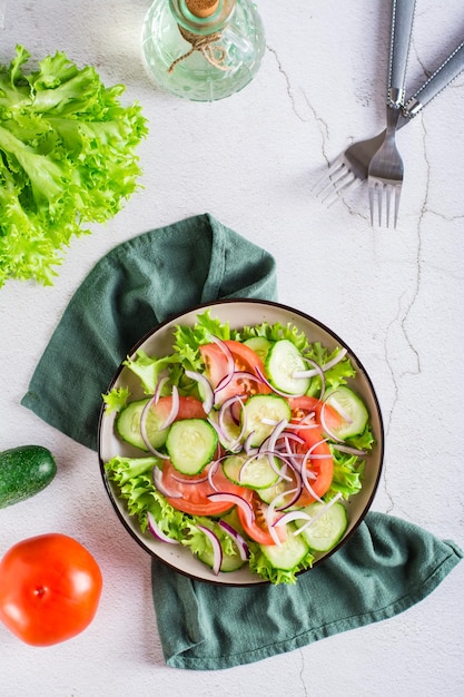 Tomato cucumber onion lettuce salad on a plate Vegetarian food Top and vertical view