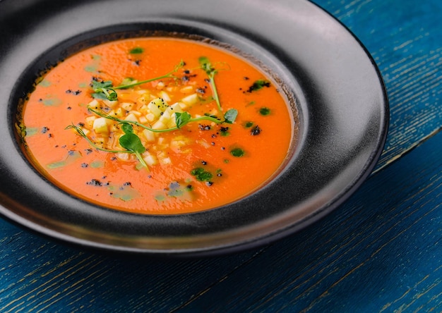 Tomato gazpacho soup on black plate