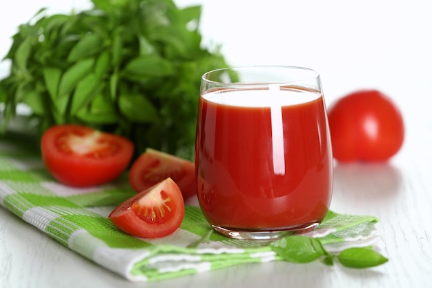 Tomato juice and fresh tomatoes on wooden table closeup