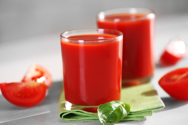 Tomato juice and fresh tomatoes on wooden table closeup