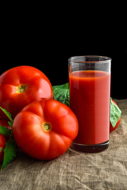 Tomato juice in glass and fresh tomatoes