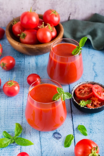 Tomato juice with basil in glasses and vegetables on the table Organic homemade drinks Vertical