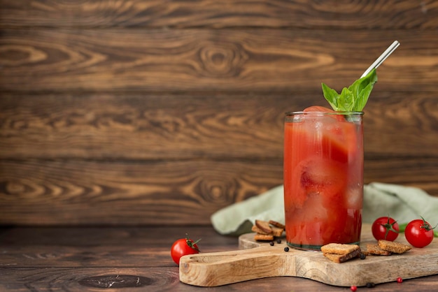 Tomato juice with spices basil and croutons in a glass on a wooden table