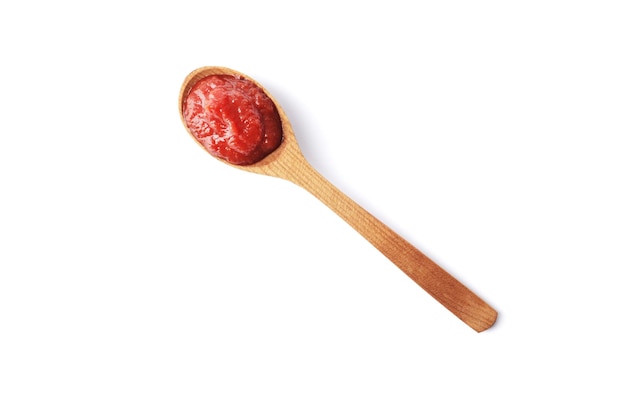 Tomato paste on a wooden spoon isolated on white background