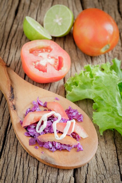 Photo tomato salad with purple cauliflowers on old wood.