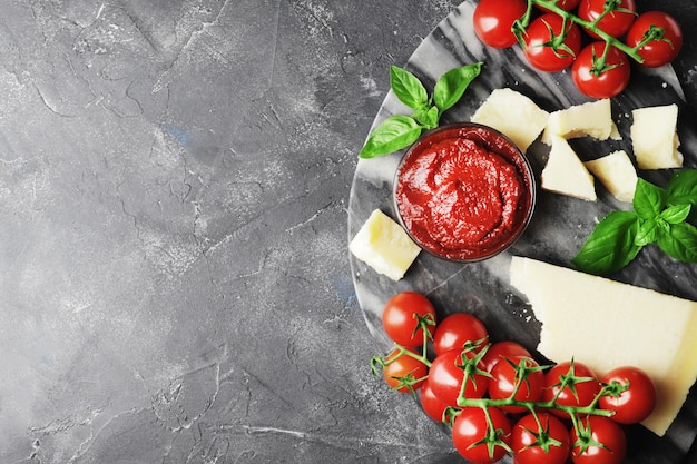 Tomato sauce in a bowl on a marble textured house with cooking ingredients