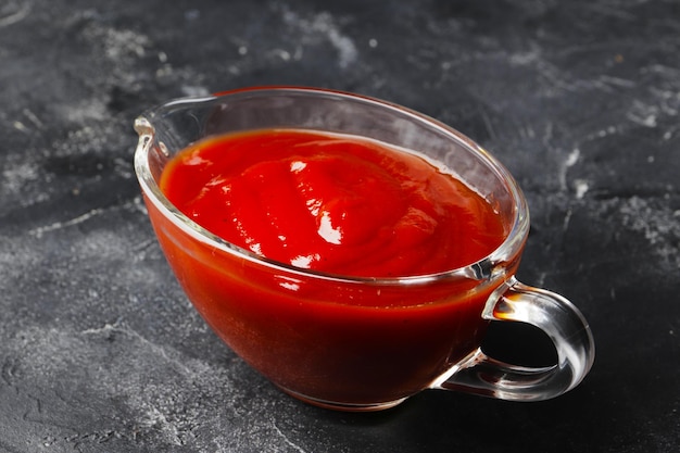 Tomato sauce in a gravy boat on a dark background