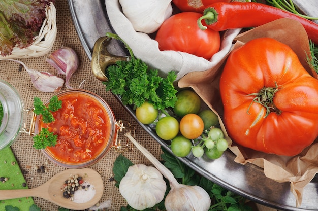 Tomato sauce and ingredients for its cooking on metal dish. Top view.