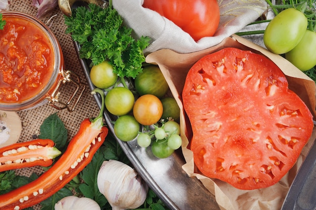 Tomato sauce and ingredients for its cooking on metal dish. Top view.