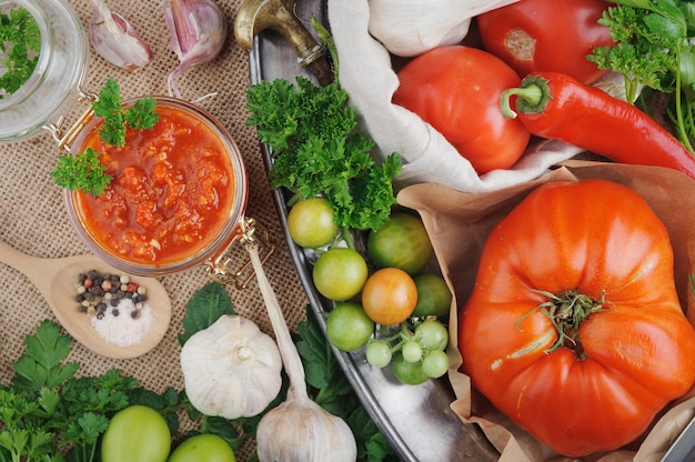 Tomato sauce and ingredients for its cooking on metal dish.