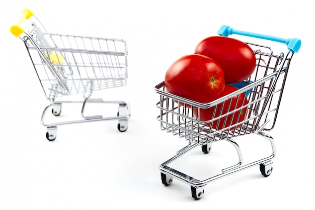 A tomato in shopping cart isolated on white background. Ripe tasty red tomatos in shopping cart. Tomato trading concept. Online shopping concept. Cart and tomato over a white background.