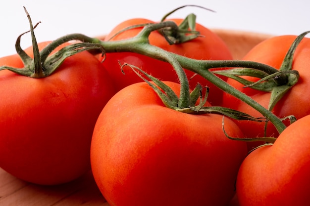 Tomato vegetables on wooden plate isolated on white close up