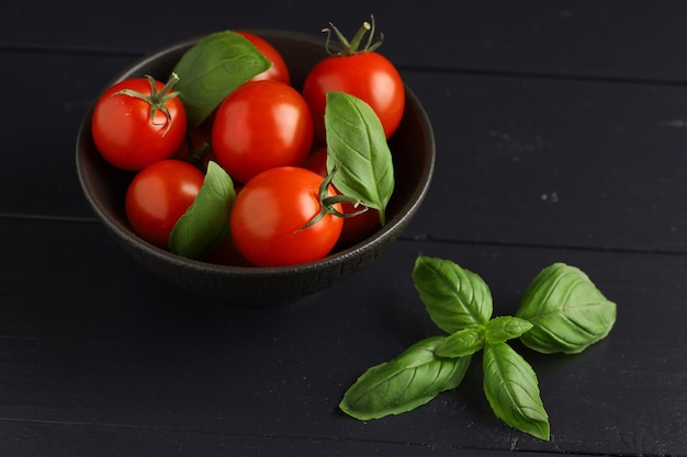 Tomatoes and basil in a bowl Fresh cherry tomatoes on a plate and basil leaves