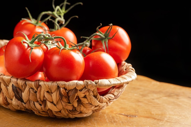 Tomatoes, beautiful tomatoes in a straw basket, over rustic wood, selective focus.