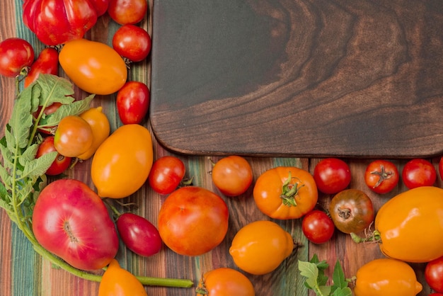 Tomatoes of different colors and types and wooden cutting board