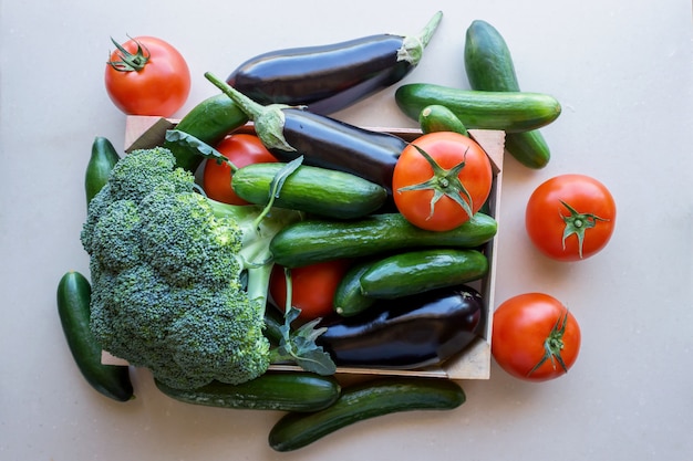 Tomatoes and eggplants, cucumbers and broccoli in a wooden crate