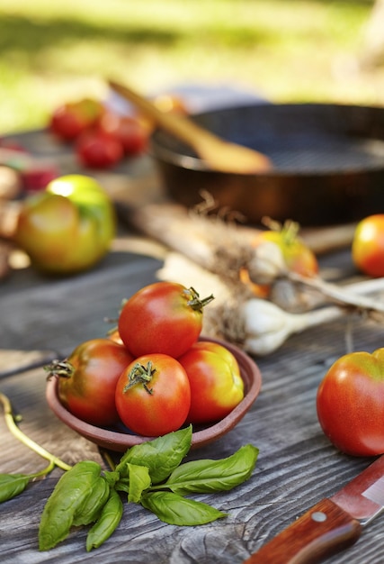 Tomatoes garlic basil on an old authentic table Frying pan in the background