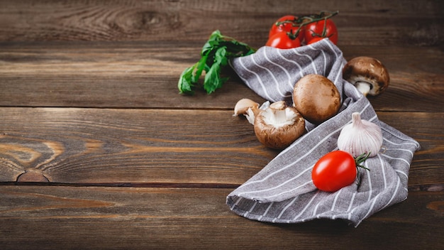 Tomatoes garlic champignons parsley pepper shaker forks and napkin on wooden background