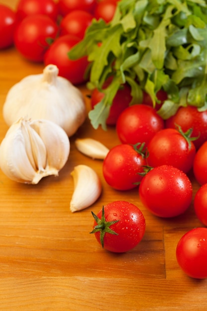 Tomatoes, garlic and rucola on wooden table, focus on foreground