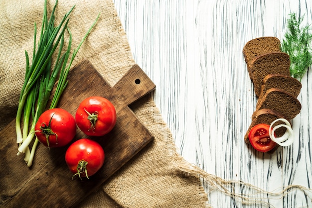 Tomatoes, green onions, dill, quail eggs, bread, on a white board