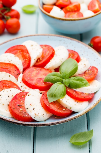 Tomatoes, mozzarella cheese, basil and spices on gray slate stone chalkboard. Italian traditional caprese salad ingredients. Mediterranean food.