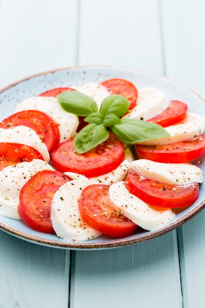 Tomatoes, mozzarella cheese, basil and spices on gray slate stone chalkboard. Italian traditional caprese salad ingredients. Mediterranean food.