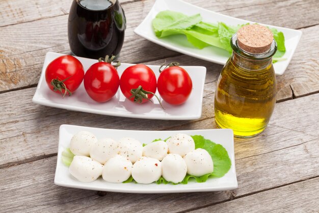 Tomatoes mozzarella and green salad leaves with condiments