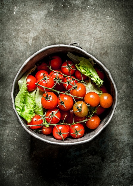 Photo tomatoes in the old pot. wet stone table.