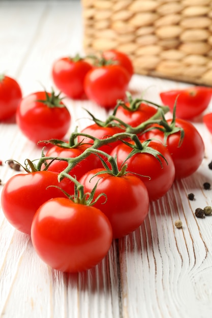 Tomatoes, pepper and basket on white wooden background, close up