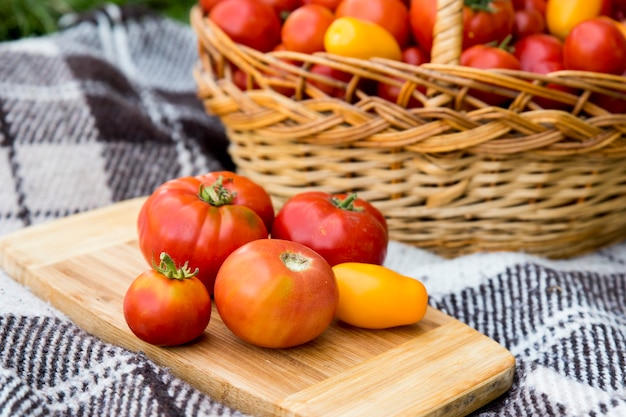 Tomatoes on a plank. Harvesting by autumn. Against the background of a large basket of tomatoes.