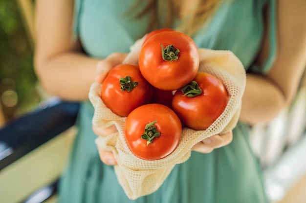 Tomatoes in a reusable bag in the hands of a young woman zero waste concept