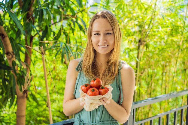 Tomatoes in a reusable bag in the hands of a young woman Zero waste concept