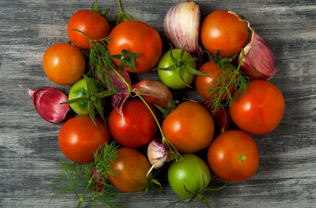 Tomatoes on the table. Tomatoes, garlic on a wooden surface. View from above. Fresh vegetables. copy space.