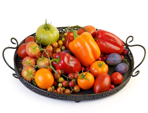 Tomatoes of various varieties and sizes on an iron tray on a wooden table