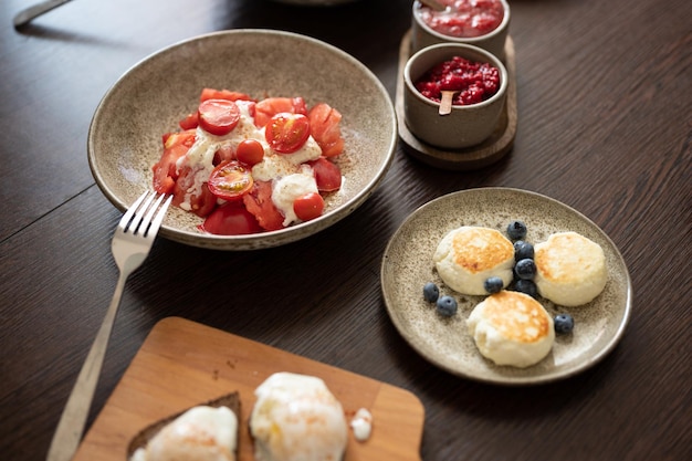 Tomatoes with Burrata cheese cheese pancakes and other food served in beautiful plates on table focus on tomatoes