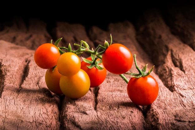 Tomatos in wooden plate on black background