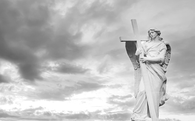 Tombstone angel with wings and cross on sky background