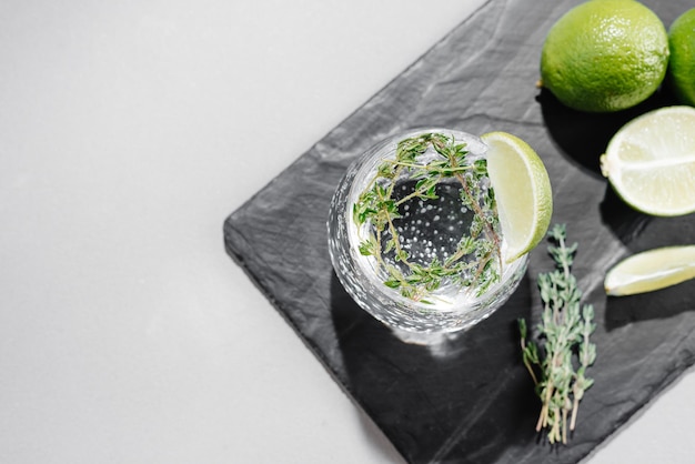 Tonic with lime and thyme cocktail on a gray background flashy food top view