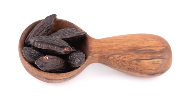 Tonka beans in wooden spoon, isolated on white