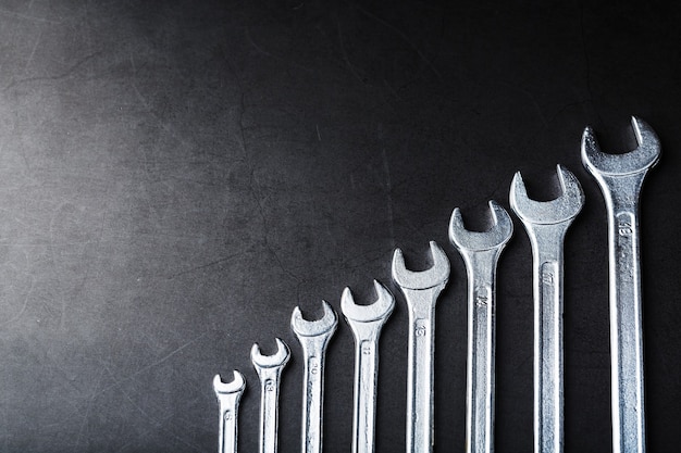 Tool wrenches in a row on a black background with free space