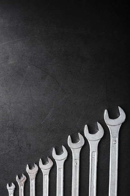 Tool wrenches in a row on a black background with free space.