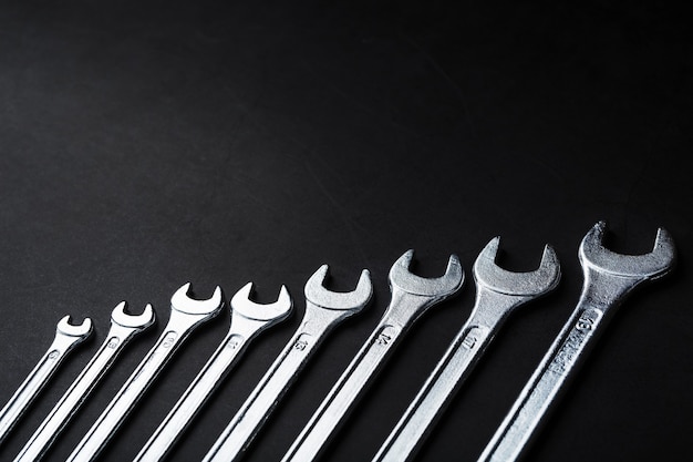 Tool wrenches in a row on a black background with free space.