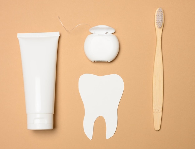 Toothbrush toothpaste and paper tooth on a brown background oral hygiene