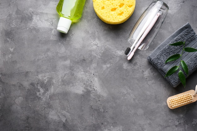 Toothbrushes in a glass with a towel on gray