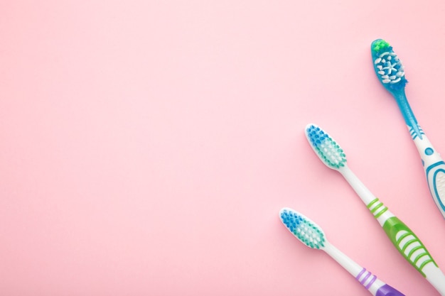 Toothbrushes on pink surface with copy space